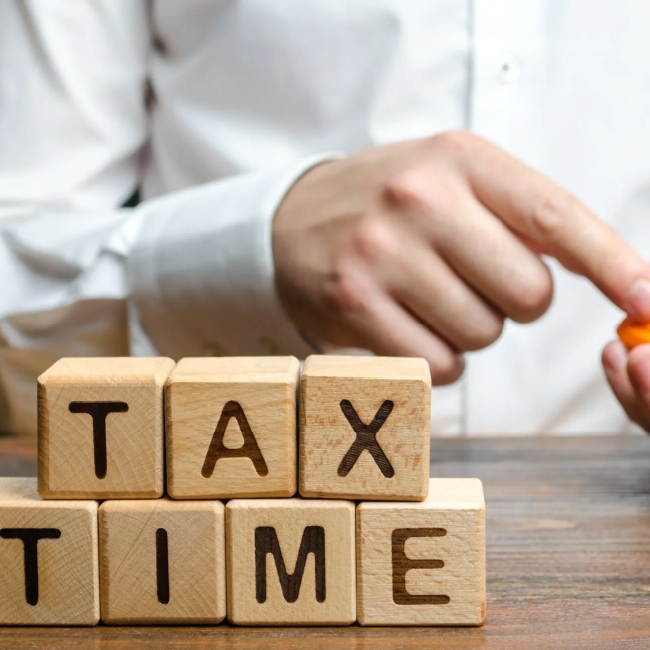 Wooden blocks spelling 'tax time' on a table.